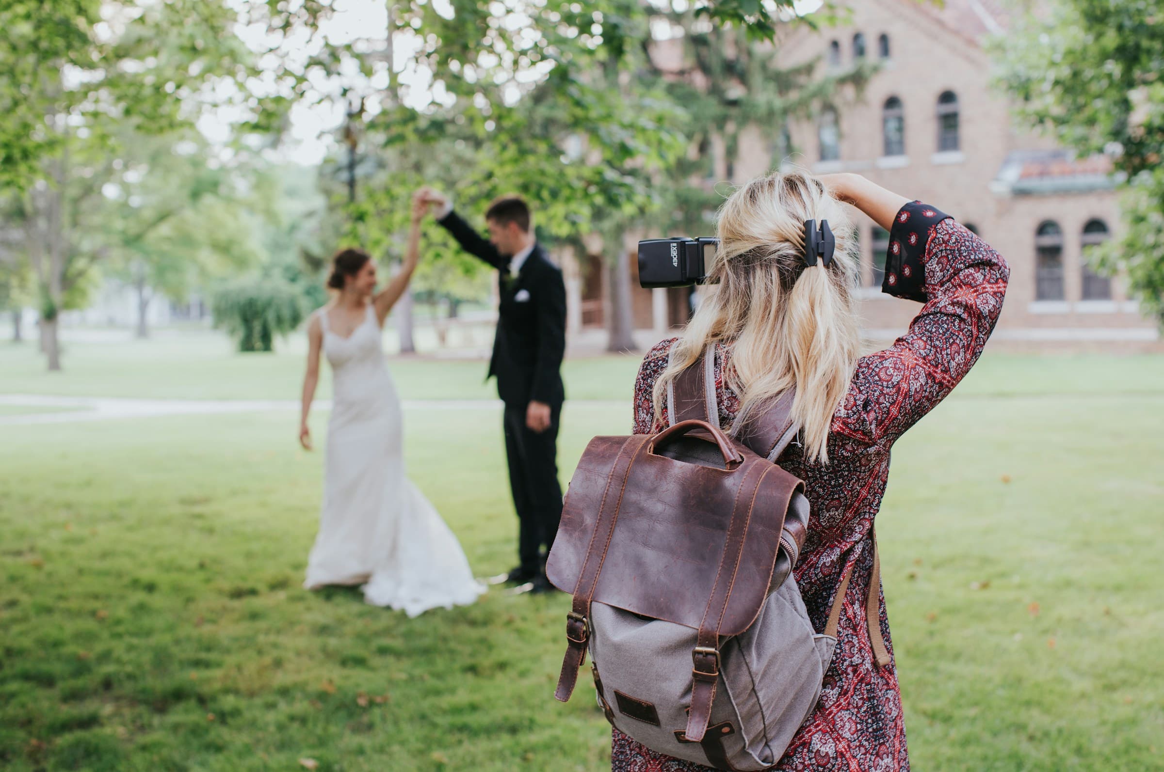 Wedding photographer taking image of bride and groom in front of wedding reception venue