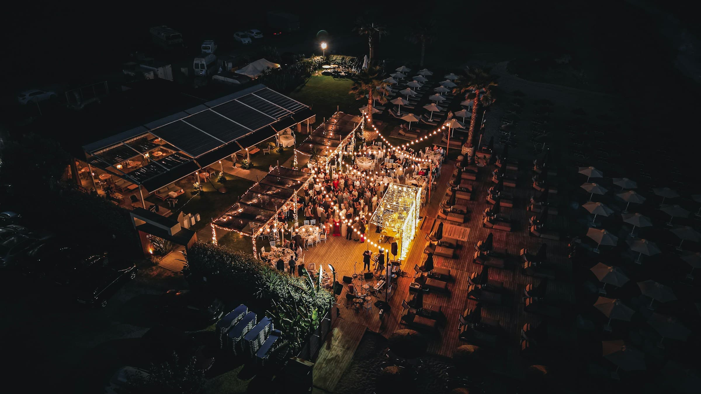 Drone videography of wedding reception lit up by string lights at night