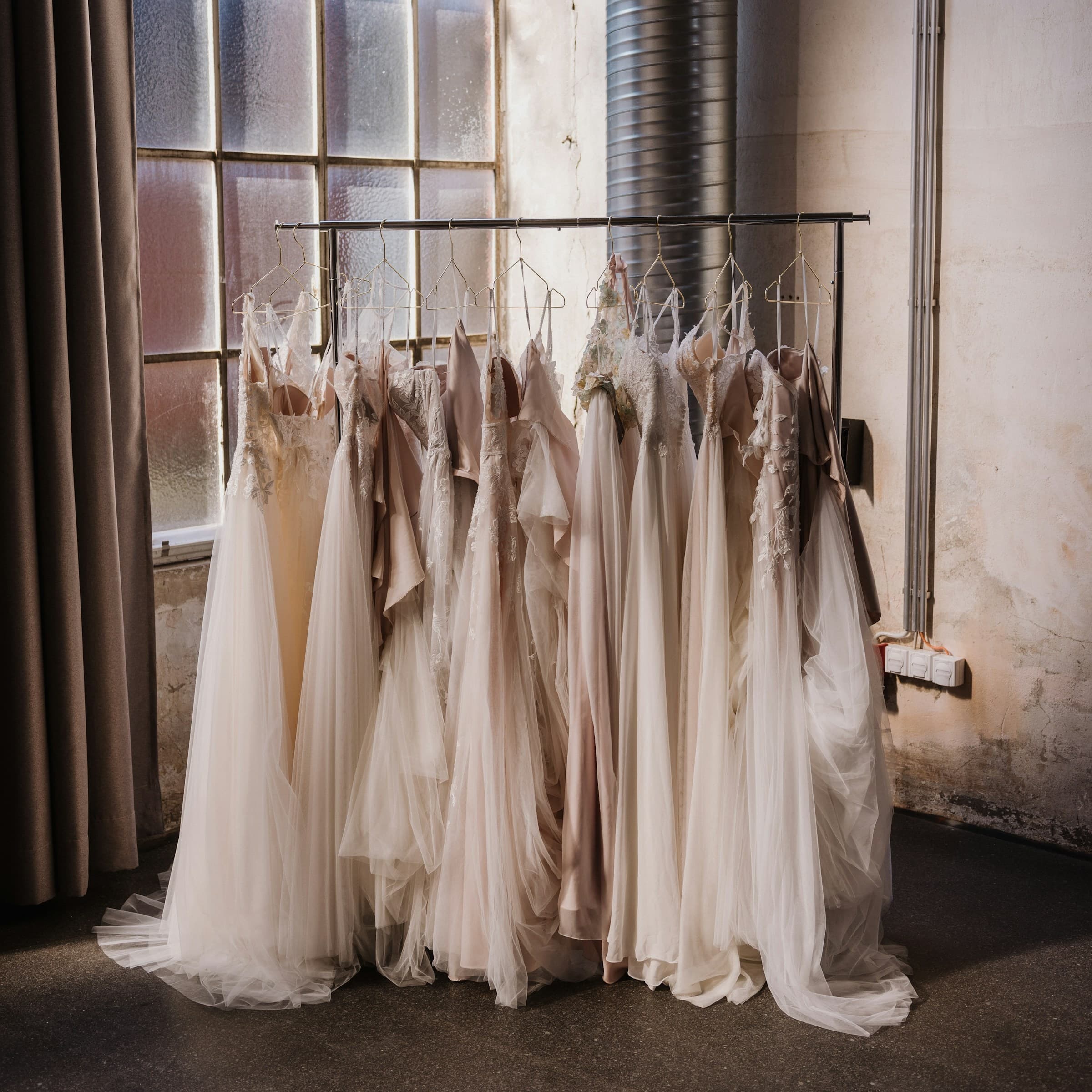 Multiple white wedding gowns on rack inside shop
