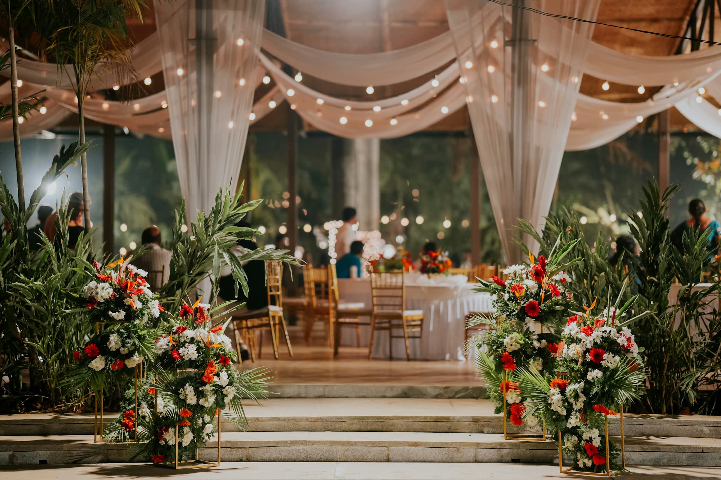 Flowers at entrance steps to wedding reception area with beautiful tables and linens