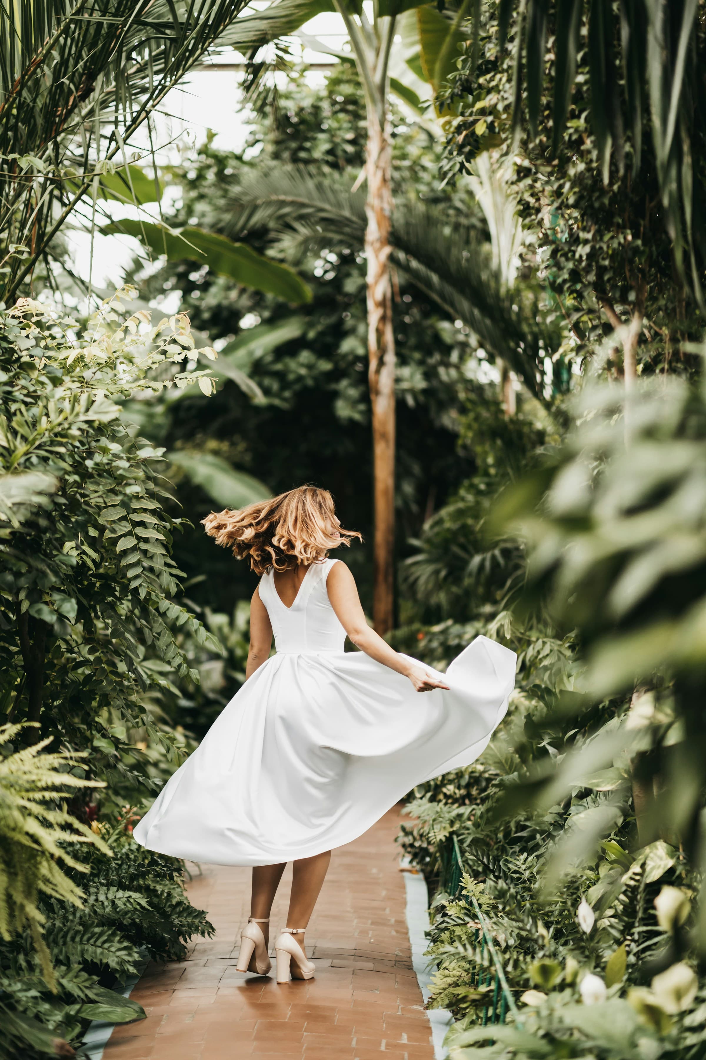 Bride running in lush green garden with hair swaying