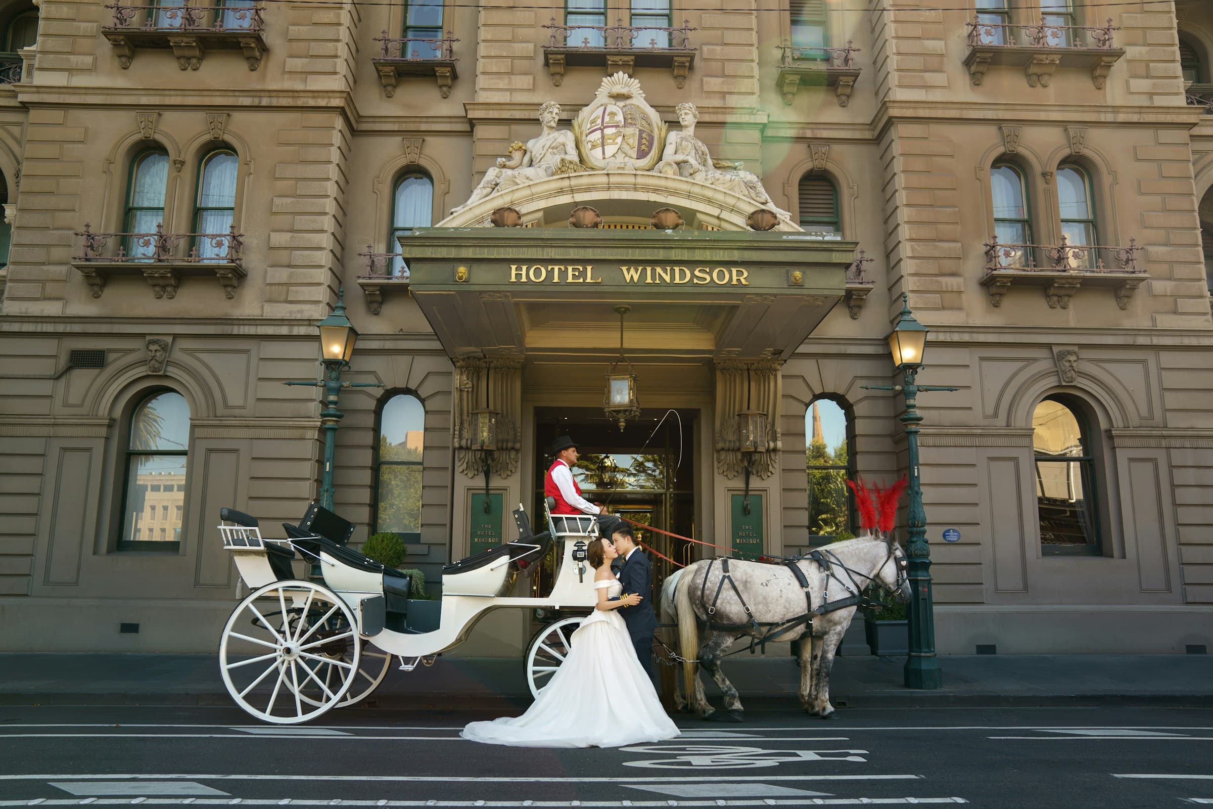 Bride and groom kiss in front of horse drawn carriage at Hotel Windsor